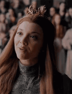 a woman with long red hair and a crown on her head is smiling .