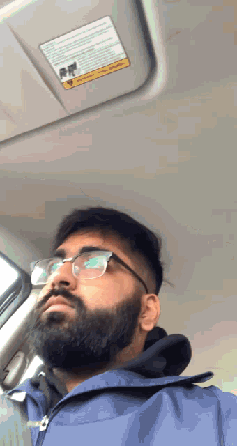 a man with glasses and a beard is sitting in a car