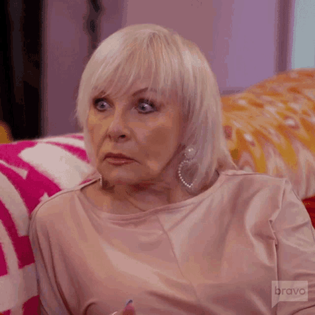 a woman in a pink shirt is sitting on a pink couch .