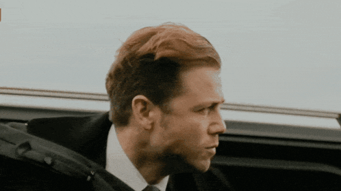 a man in a suit and tie is looking out of a car window