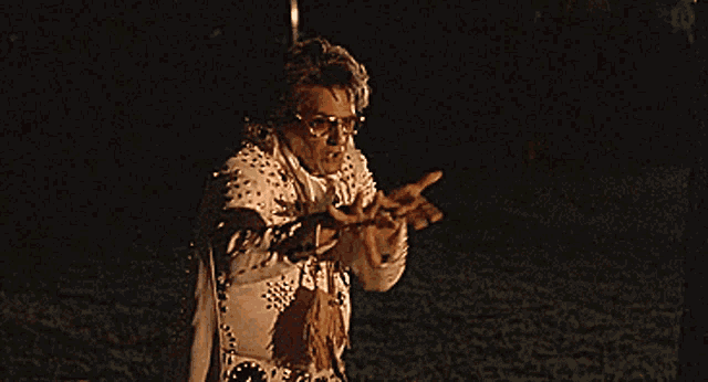a man in a elvis costume is standing in a dark field