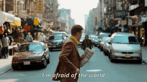 a man walking down a street with the words " i 'm afraid of the world "
