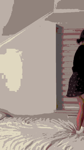 a woman in a black skirt is standing on a bed in front of a window