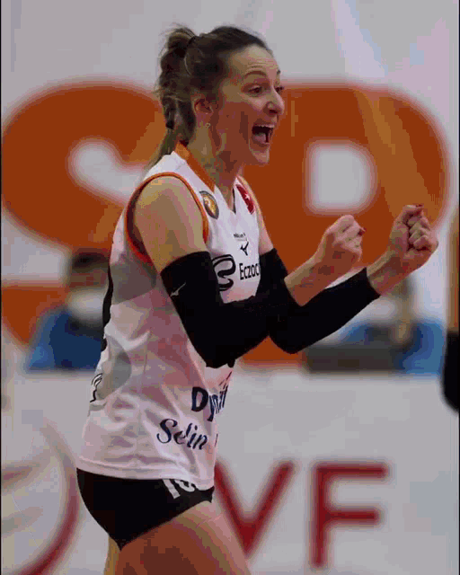 a female volleyball player is celebrating a point with her fist in the air ..