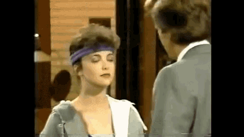 a man and a woman are standing next to each other . the woman is wearing a purple headband .