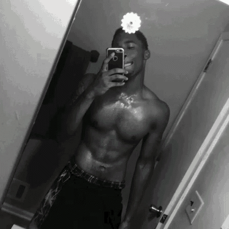 a shirtless man is taking a selfie with a flower on his head