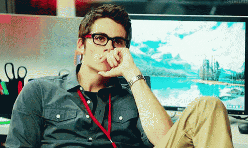 a young man wearing glasses is sitting in front of a computer monitor .