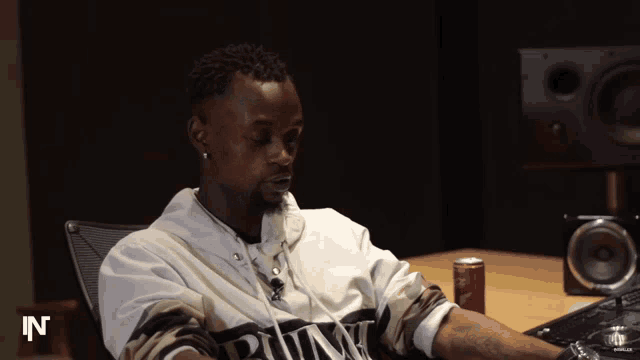 a man sits at a desk with a can of coke in front of him with the letter n on it