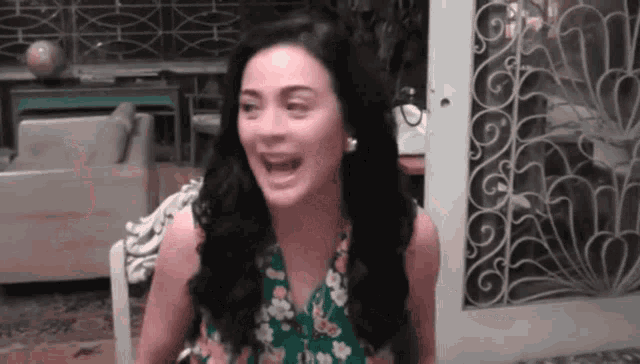 a woman in a green dress is laughing in front of a sliding glass door .