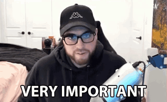 a man wearing glasses and a hat says very important while holding a microphone .