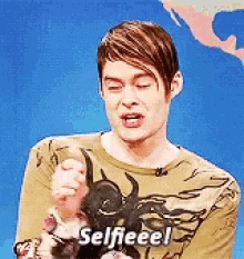 a man is holding a stuffed animal and saying selfeee !