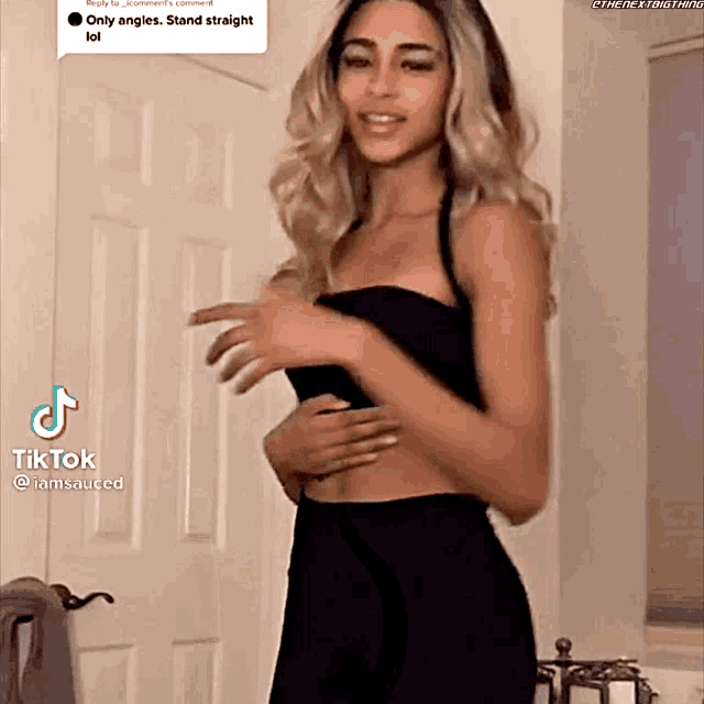 a woman in a black dress is standing in front of a door with a tiktok icon on the bottom right corner