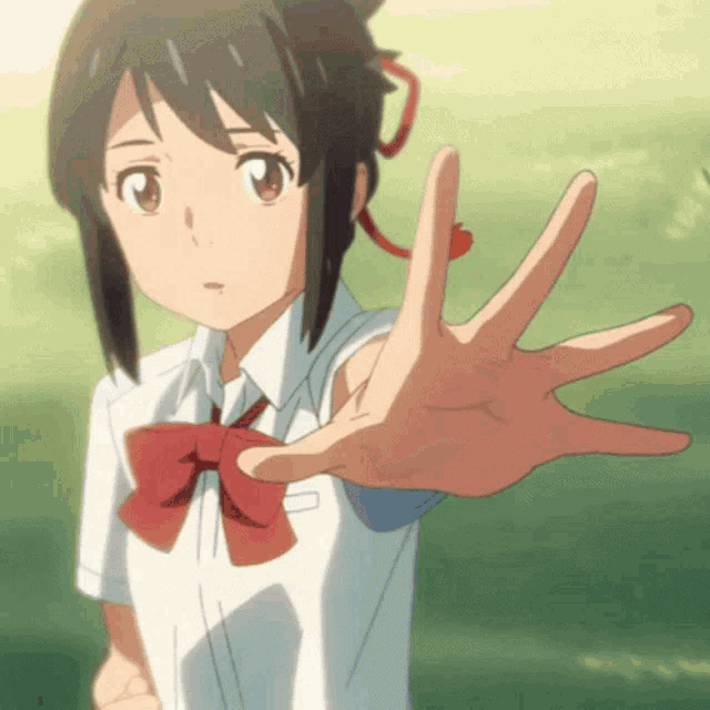 a girl in a school uniform with a red bow reaches out her hand
