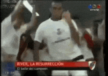 a man in a white shirt is singing into a microphone while dancing in front of a crowd .