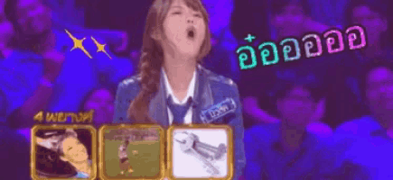 a woman is yawning while holding a picture of a wrench in front of a crowd of people .