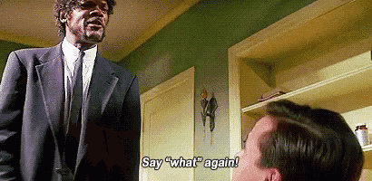 a man in a suit and tie is standing next to another man in a room and talking to him .