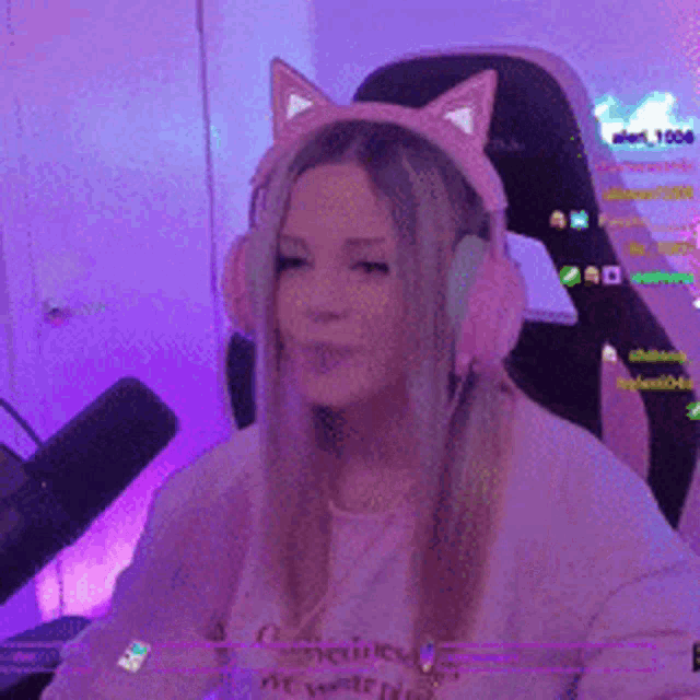 a woman wearing headphones with cat ears is sitting in a pink chair