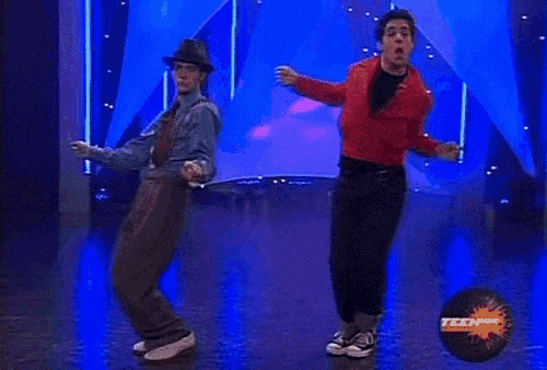 two men are dancing on a stage with a nickelodeon logo in the foreground .