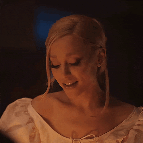 a woman with blonde hair is wearing a white dress and earrings