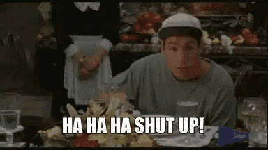 a man in a baseball cap is sitting at a table in a restaurant and says `` ha ha ha shut up '' .