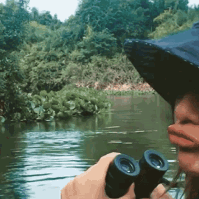a person is looking through binoculars at a river