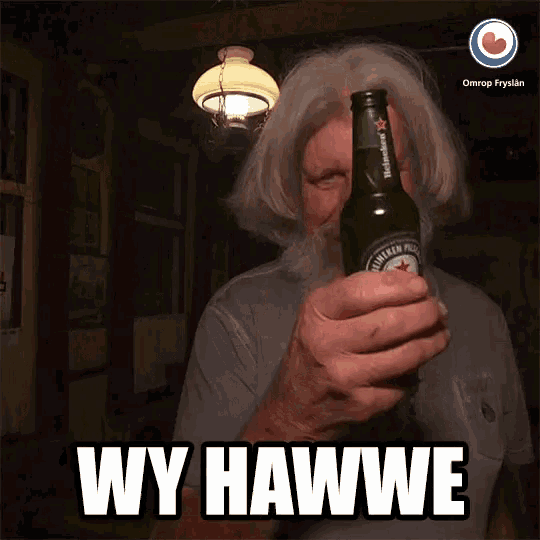 a man with a beard is holding a heineken beer bottle in front of his face