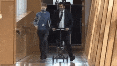a man in a suit and tie is riding a small scooter