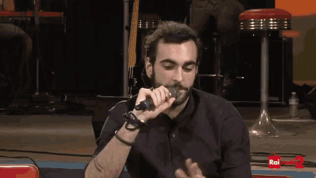a man singing into a microphone with rai radio 2 written on the bottom right