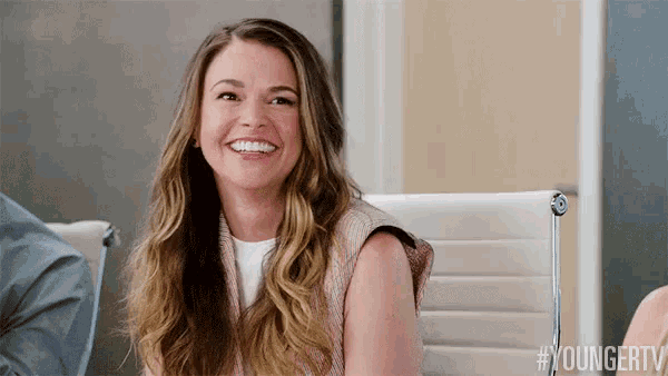 a woman is smiling while sitting in a white chair .