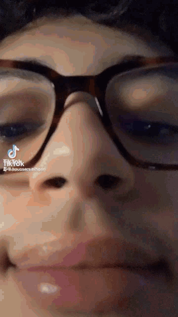 a close up of a person wearing glasses with tiktok written on the bottom right