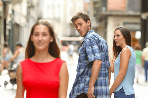a woman in a red dress is looking at a man in a blue plaid shirt walking down the street .