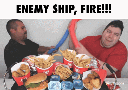 two men are playing with a hula hoop over a table of wendy 's chicken and fries
