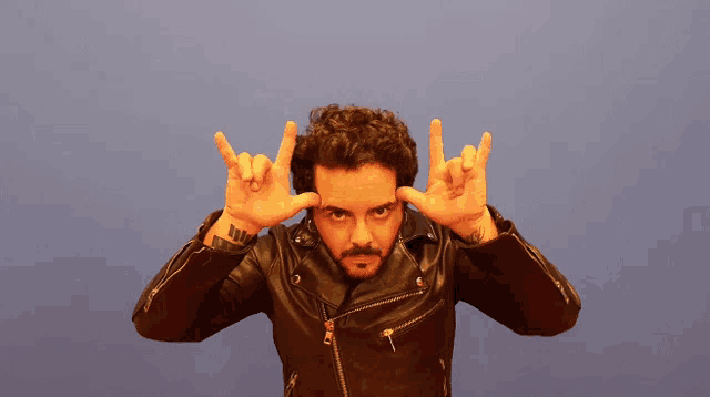 a man in a leather jacket is making a devil horns sign