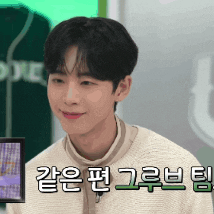 a young man wearing a white sweater is smiling in front of a green shirt that says ' doyle ' on it
