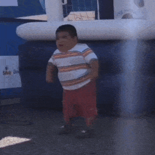 a little boy is dancing in front of an inflatable volleyball net
