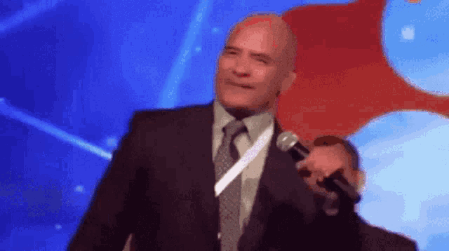 a man in a suit and tie is talking into a microphone .