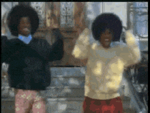 two people with afros are dancing together in front of a building .