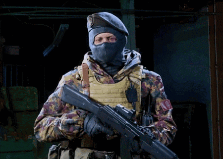 a soldier wearing a mask and beret is holding a rifle