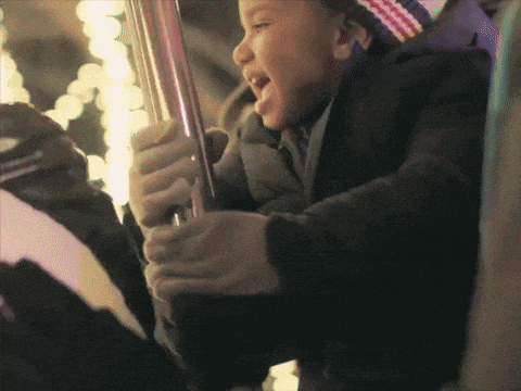 a little boy is riding a carousel and making a face