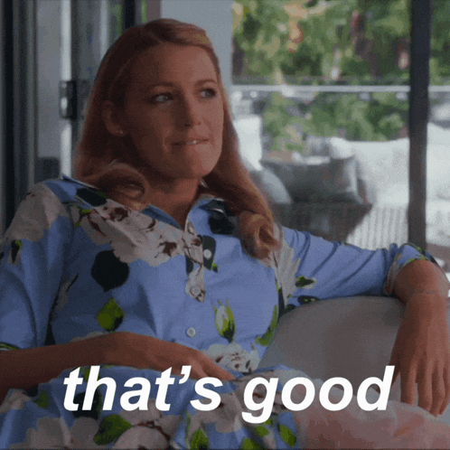 a woman in a blue floral shirt is sitting on a couch with the words that 's good written below her