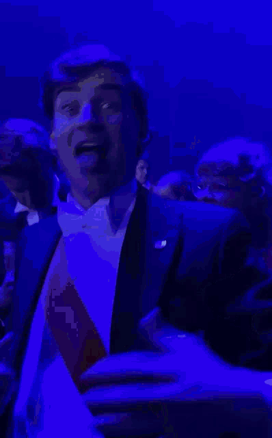 a man in a tuxedo has a medal around his neck that says j.m.