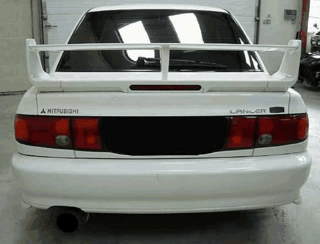 the rear end of a white mitsubishi lancer with a spoiler on top of it .