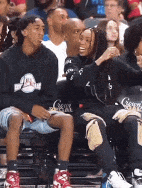 a man wearing a black sweatshirt that says crown on it sits next to a woman