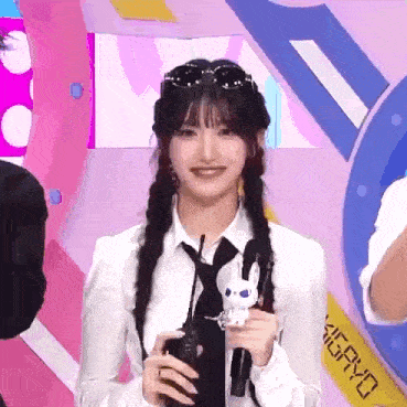 a girl in a white shirt and tie is holding a toy bunny .