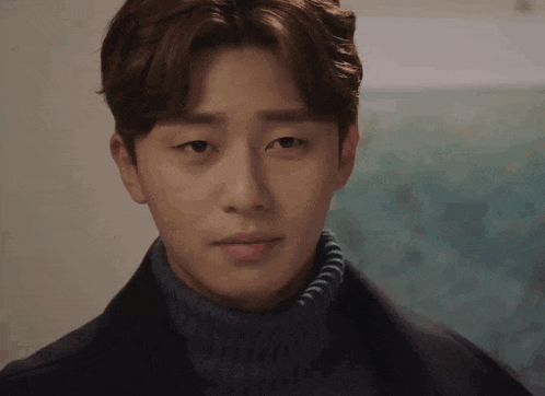 a close up of a man wearing a turtleneck sweater and a black coat