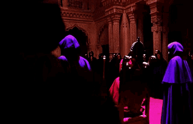 a group of people in purple robes are standing around a throne