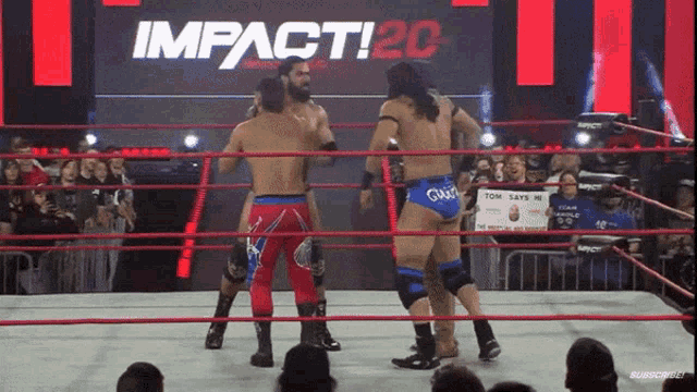 wrestlers in a ring with a sign that says impact 20 in the background