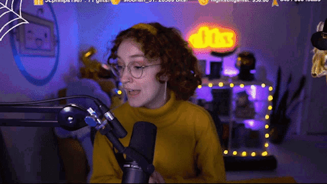 a woman in a yellow sweater is speaking into a microphone in front of a sign that says ' 00 ' on it