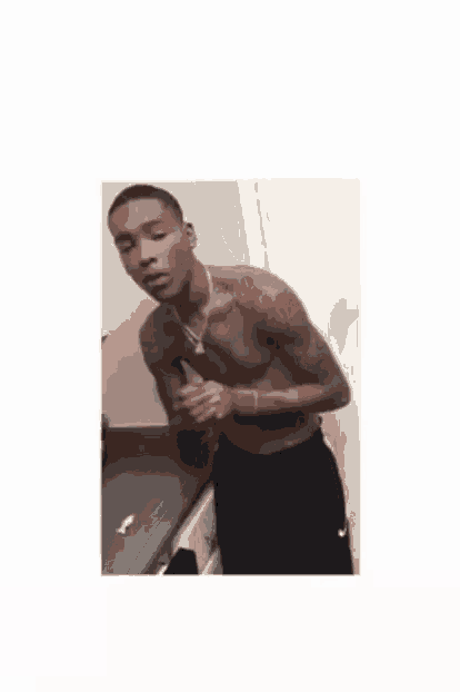 a shirtless man with tattoos on his arms and chest is standing in front of a sink .