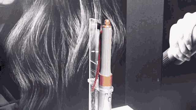 a person is holding a hair dryer in front of a black and white drawing of a woman 's hair